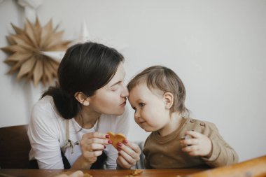 Sevimli kız ve anne dağınık masada birlikte Noel kurabiyesi yapıyorlar. Annesinin zencefilli kurabiye hamuru kesmesine yardımcı olan tatlı bebek. Noel tatili için aile hazırlıkları