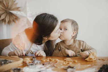 Sevimli küçük kız ve anne Noel kurabiyesi yapıyorlar. Mutlu anne küçük tatlı kızını öpüyor. Sevgili anne-kız anları, mutlu aile anları. Tatil hazırlıkları