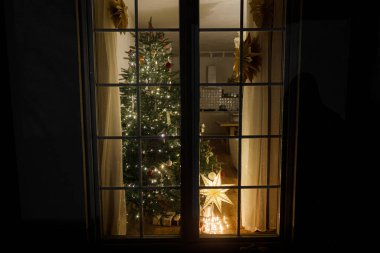 Süslü Noel ağacı, hediyeler, parlayan ışıklar ve gece rahat oturma odasında yıldız, pencereden bakmak. Mutlu Noeller ve mutlu Noeller! Atmosferik Noel arifesi, büyülü zaman