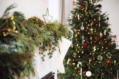 Mutlu Noeller! Köknar dalları, Noel yıldızı, çoraplar ve modern oturma odasındaki ışıklarla süslenmiş şık bir şömine. Atmosferik Noel zamanı, kış tatili