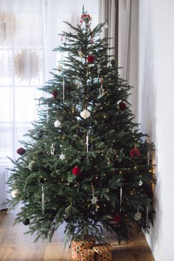 Modern kağıt takılar, süsler, klasik yıldızlar, ışıklar ve hediye kutuları olan şık bir Noel ağacı. Kış tatili dekorasyonu, atmosferik noel zamanı