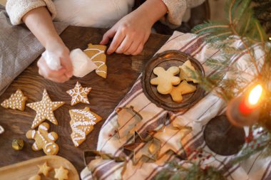 Zencefilli kurabiyeleri süsleyen kadın, köknar dalları ve metal kesicilerle kırsal masada şekerle kaplanmış olarak yatıyordu. Holiday Aile geleneği