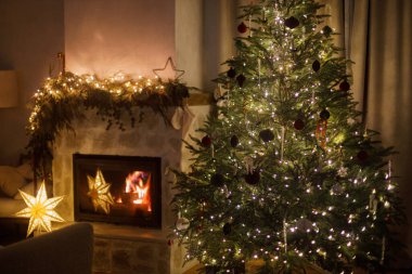 Mutlu Noeller ve mutlu tatiller! Büyülü bir arifede İskandinav oturma odasında ışıklarla, süslerle ve modern şöminelerle süslenmiş Noel ağacı. Şenlikli ev