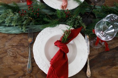 Modern tabaklar, kırmızı ve yeşil peçeteler, çatal bıçak, cam, köknar dalları, kırmızı böğürtlen, ahşap masa üzerinde mum. Mutlu Noeller.!