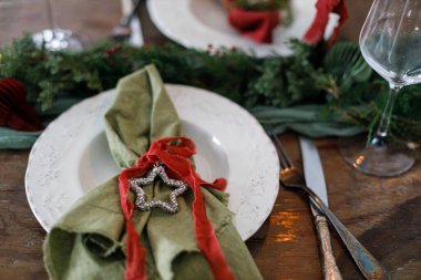 Modern tabaklar, kırmızı ve yeşil peçeteler, çatal bıçak, köknar dalları, kırmızı böğürtlenler, ahşap masadaki yıldız. Mutlu Noeller ve mutlu tatiller!