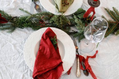Modern tabak, kırmızı ve yeşil peçeteler, çatal bıçak, cam, köknar dalları, keten masa örtüsünün üzerindeki kırmızı böğürtlenler. Mutlu Noeller ve mutlu tatiller!