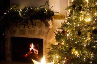 Şık dekore edilmiş Noel ağacı ve geceleri modern rahat oturma odasında çoraplarla yanan şömine. Mutlu Noeller ve mutlu Noeller! Atmosferik Noel arifesi, büyülü tatil zamanı.