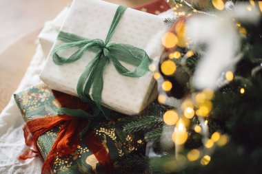 Şık Noel hediyeleri. Mutlu Noeller ve mutlu tatiller! Noel hediye kutuları, yılbaşı ağacına karşı ışıklar bokeh. Tatil afişi, atmosferik kış zamanı