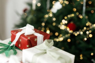 Noel hediyeleri. Noel hediye kutuları masanın üzerinde şenlikli kurdeleler ve arka planda altın ışıklı Noel ağacı süslemeleri. Mutlu Noeller! Tatil afişi