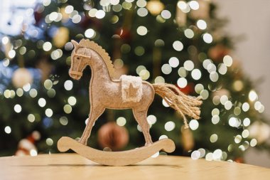 Mutlu yıllar 2026! Altın ışıklı Noel ağacının arka planında Noel atı kırsal oyuncağı. Sembol 2026. Boşluğu kopyala