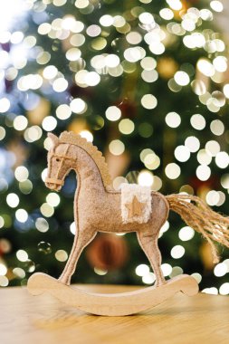 Altın ışıklı Noel ağacının arka planında Noel atı kırsal oyuncağı. Sembol 2026. Mutlu yıllar 2026! Boşluğu kopyala