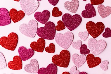 Sevgililer Günün kutlu olsun! Pembe ve kırmızı parıltılı kalpler pembe kağıt arka planda yatıyordu. Modern sevimli aşk afişi. Kalpli sevgililer günü kartı