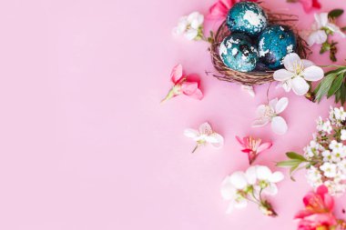 Mutlu Paskalyalar! Yuvasında kiraz çiçekli paskalya yumurtaları pembe arka planda yatıyordu. Stil yay şablonu ve metin için boşluk. Paskalya tebrik kartı ya da afişi
