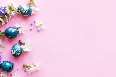 Paskalya düzlüğü. Paskalya yumurtaları ve pembe arka planda kiraz çiçekleri. Paskalya kutlaması, sezon kutlaması. İlkbahar modern çiçek bayrağı