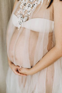 Güzel hamile kadın kucağında bebek şişliği ve yumuşak ışıkta poz veriyor. Anneler Günün kutlu olsun! Sağlıklı hamilelik ve doğurganlık kavramı. Peçeli hamile kadın, hassas annelik.