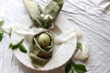 Mutlu Paskalyalar! Tavşan kulaklı peçeteye boyanmış yumurta ve tabakta bahar çiçekleri. Paskalya kutlaması masası, tatil durgun hayatı. Tebrik kartı ya da afiş, metin için boşluk