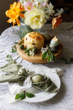 Paskalya kutlaması. Tavşan kulaklı paskalya yumurtaları peçete, paskalya ekmeği, mum ve kiraz çiçekleri keten üzerinde, yazı için yer. Atmosferik otantik Paskalya sofrası, durgun yaşam