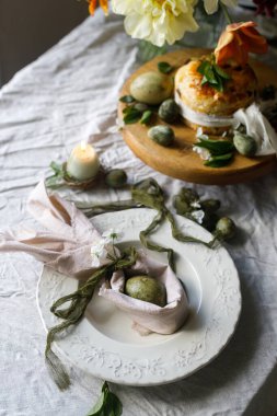 Paskalya kutlaması. Tavşan kulaklı paskalya yumurtaları peçete, paskalya ekmeği, mum ve kiraz çiçekleri keten üzerinde, yazı için yer. Atmosferik otantik Paskalya sofrası, durgun yaşam