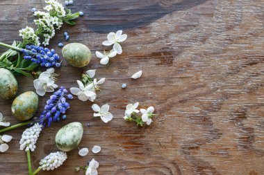 Mutlu Paskalyalar! Bahar çiçekli Paskalya yumurtaları kırsal ahşap arka planda yatıyordu. Stil yay şablonu ve metin için boşluk. Paskalya tebrik kartı veya asgari afiş