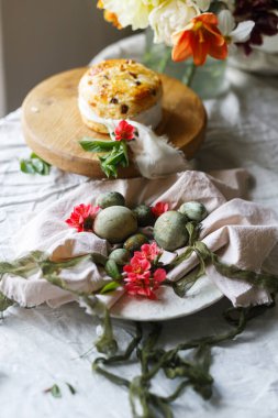 Paskalya kutlaması. Şık yeşil paskalya yumurtaları, paskalya ekmeği ve çarşaf peçetesinde kiraz çiçekleri, yazı için yer. Atmosferik otantik Paskalya sofrası, durgun yaşam