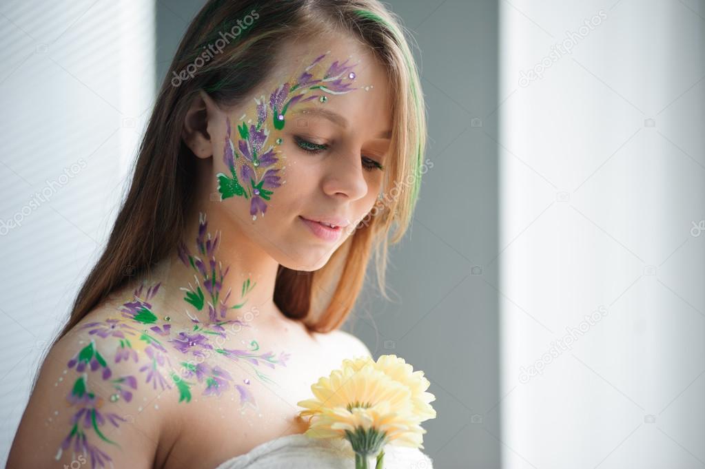 Girl with flower bodyart and sunflowers bouquet