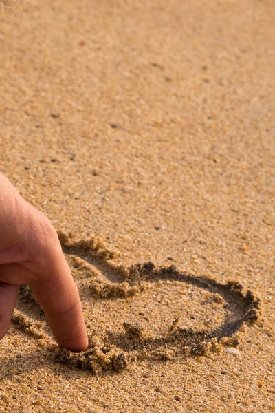 Parmak bir aşk kalp kuma çizer.