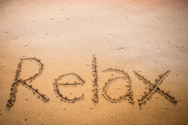 Розслабтеся, записані в пісок на пляжі — стокове фото