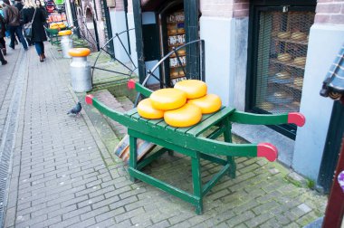 Tezgahın üzerinde büyük sarı peynir kafalar var. Dükkanın yakınındaki sokakta peynir kafalar