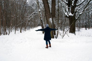 Kış. Bir kadın ormanda yağan karla sevinir. Ocak ayında ormanda.