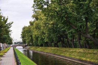 Kanalın kemerli bir köprüsü ve yeşil ağaçları olan panoramik manzarası.