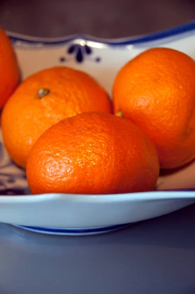 站在玻璃桌上的白盘上的橘子橘子橘子橘子 — 图库照片