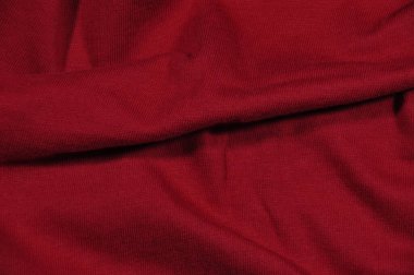 Background, texture. Fragment of red fabric with a small pattern and a fold.