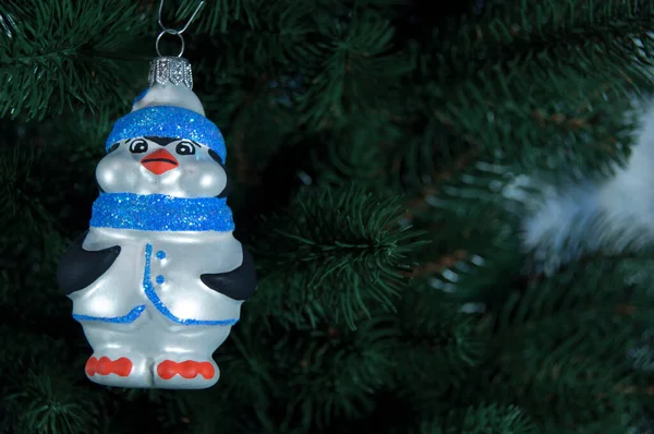 Mutlu yıllar ve mutlu Noeller. Noel ağacının dalındaki Noel oyuncağı penguen.