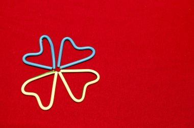 Kırmızı arka planda, kablodan yapılmış dört kalp. İki kalp mavi ve ikisi beyaz. Arkaplan, tasarım.