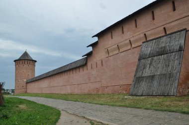 Kulesi olan eski bir kırmızı tuğla duvar manzarası. Duvardaki yol taşla döşenmiş..