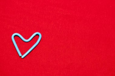 Kırmızı zemin üzerinde kablodan yapılmış küçük kalp. Arka plan, doku. Aşıkların tatili.