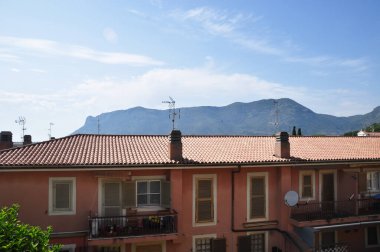 Kentsel fayanslı çatıların panoramik manzarası, dağlar ve mavi gökyüzü. Yaz güneşli bir gün.