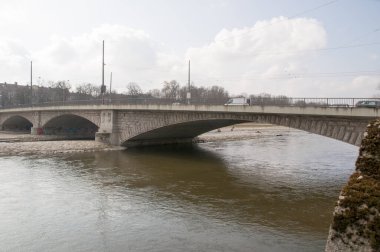 Sığ bir nehrin üzerindeki kemerli taş köprü. Şehrin yaz manzarası..