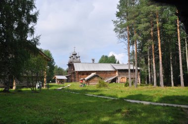 Kütük evlerin ve eski kilisenin panoramik manzarası. 03 Ağustos 2020, Malye Korely, Arkhangelsk, Rusya