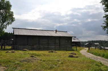 Odunlardan yapılmış eski bir ahşap evin panoramik manzarası, ahşaptan yapılmış bir çit, çimenli bir çayır ve ahşap binalar. 03 Ağustos 2020, Arkhangelsk, Rusya.