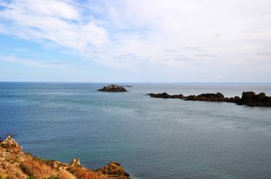 Okyanusun panoramik manzarası, küçük adalar ve uzak bir adada deniz feneri..