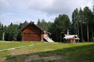 Odunlardan yapılmış eski bir ahşap ev ve açıklıktaki ahşap bir kuyu. 03 Ağustos 2020, Arkhangelsk, Rusya.