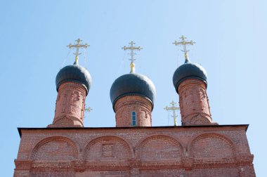 Bir Ortodoks katedralinin üç kubbesi. Mavi gökyüzünde haçları olan güzel kubbeler. Kırmızı tuğlalı katedral.