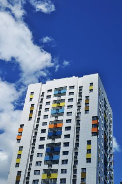 Yeni evin üst katları. Mavi gökyüzü ve bulutların arka planında yeni evin görüntüsü. Şehirde yaz..