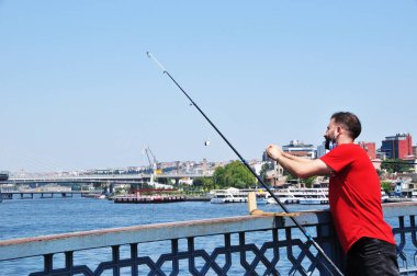 Bilinmeyen bir balıkçı köprüden balık yakalar. İstanbul 'da Galata Köprüsü' nden bir adam balık tutuyor. Balık tutmaya. 10 Temmuz 2021 İstanbul, Türkiye