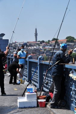 Balıkçılar Galata Köprüsü 'nde balık yakalar. Güneşli bir gün. 09 Temmuz 2021, İstanbul, Türkiye.