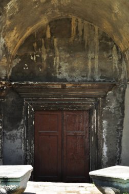 Taş bir duvar ve büyük ahşap bir kapı. Eski bordo kapı..