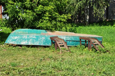 Tekne yere indi. Yerde boyası soyulmuş metal bir tekne var. Tekne tamir için hazır..