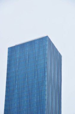 Gökdelen mavi gökyüzüne karşı. Geniş pencereli yüksek binalar.