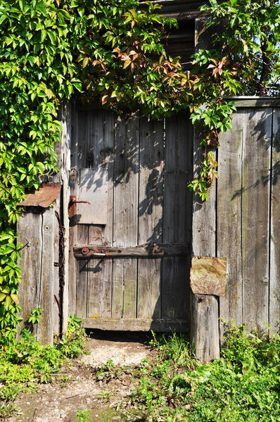Old wooden door. The front door is made of planks. The boards turned gray. Background, texture.